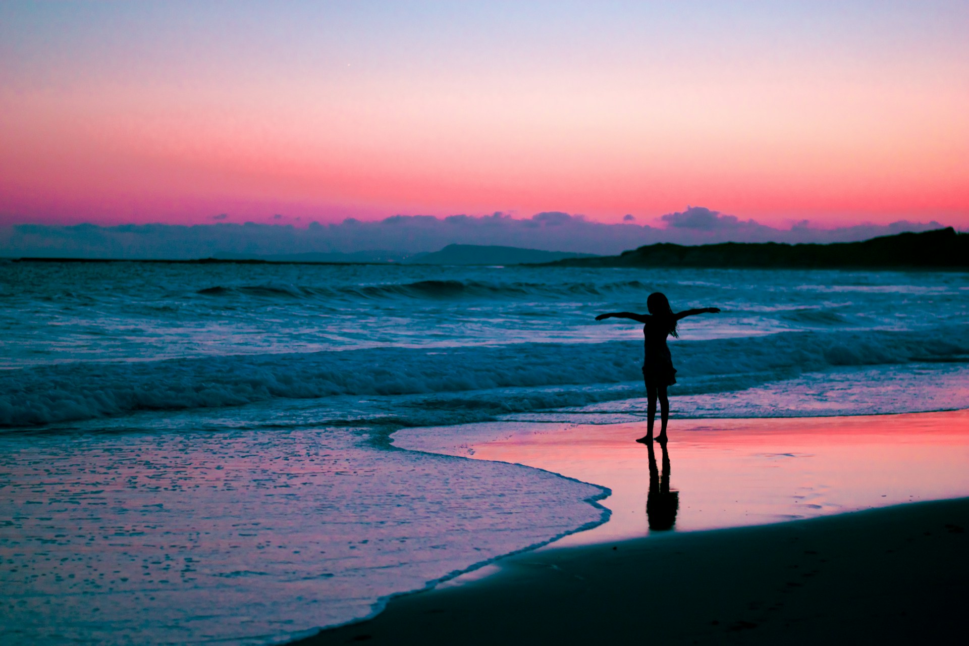 Girl on a beach with arms out in freedom pose 